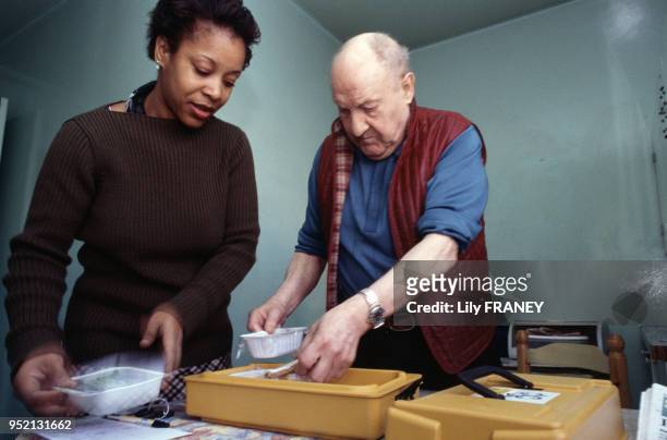Aide à domicile livrant des repas préparés chez un homme âgée à Vitry-sur-Seine, en janvier 2001, dans le Val-de-Marne, France.