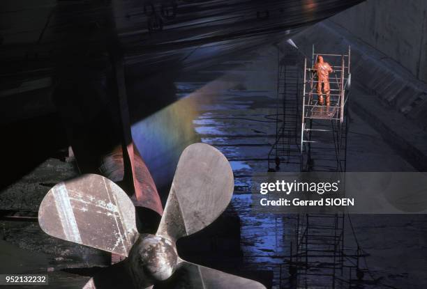 Ouvrier nettoyant la coque d'un bateau dans le chantier naval de Saint-Nazaire, en octobre 1987, en Loire-Atlantique, France.