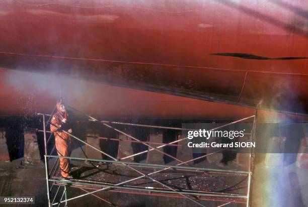 Ouvrier nettoyant la coque d'un bateau dans le chantier naval de Saint-Nazaire, en octobre 1987, en Loire-Atlantique, France.