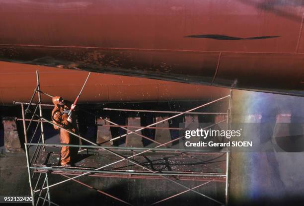 Ouvrier nettoyant la coque d'un bateau dans le chantier naval de Saint-Nazaire, en octobre 1987, en Loire-Atlantique, France.