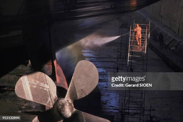 Ouvrier nettoyant la coque d'un bateau dans le chantier naval de Saint-Nazaire, en octobre 1987, en Loire-Atlantique, France.
