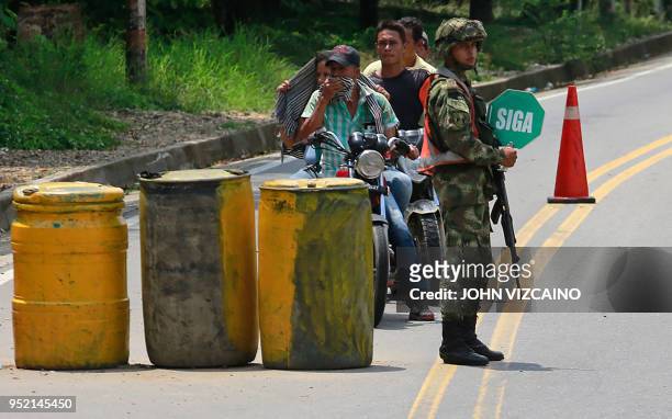 Soldiers stands guard in a streets of Tibu, in the region of Catatumbo, Norte Santander Department, in northeastern Colombia, talk to a woman and a...