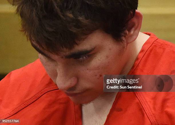 Florida school shooting suspect Nikolas Cruz, who usually sits in court with his head down, briefly looks up during a delay in his hearing in front...