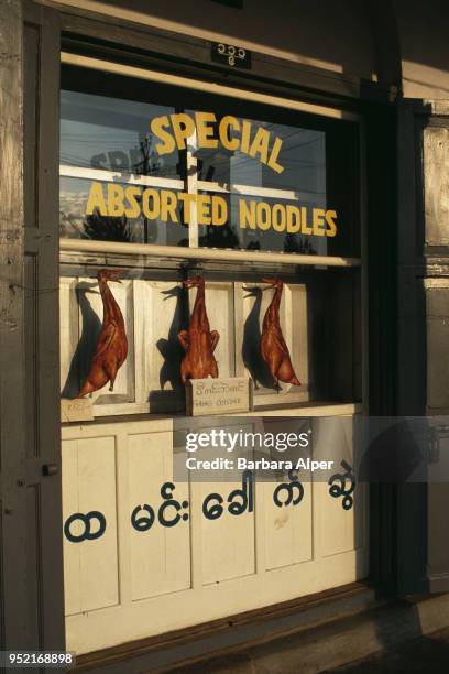 Cooked ducks and a sign advertising 'Peking Cuisine' in a restaurant window in the city of Taunggyi in Myanmar , February 1988.