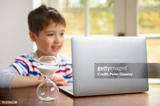 6 year old boy on laptop with timer - parental control stock-fotos und bilder