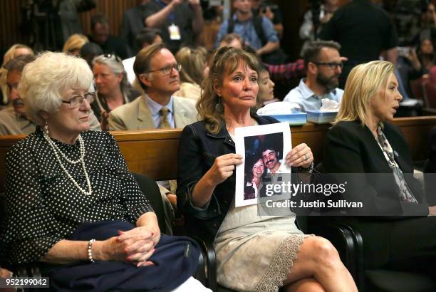 An attendee holds a photo of Cheri Domingo and her boyfriend Gregory Sanchez, who were killed in 1981, as she sits in the courtroom during the...