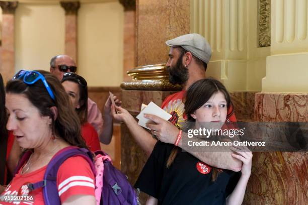 Aspen Malmberg holds her dad, Jason as he hands out postcards for teachers to write their legislators during a teachers rally for more educational...