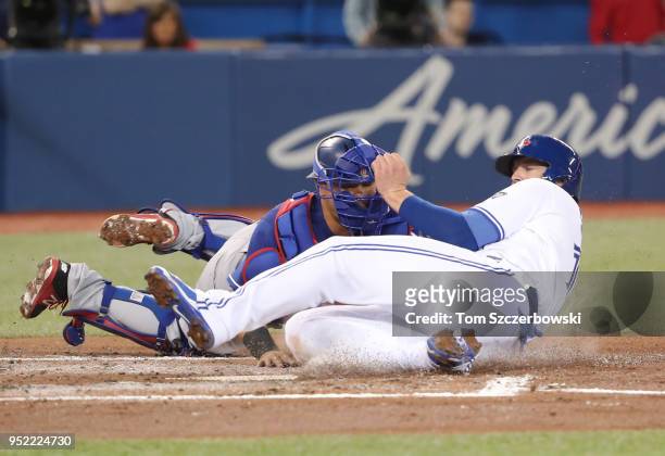 Justin Smoak of the Toronto Blue Jays is tagged out at home plate in the first inning during MLB game action as Juan Centeno of the Texas Rangers...