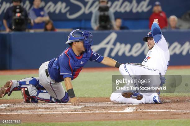 Justin Smoak of the Toronto Blue Jays is tagged out at home plate in the first inning during MLB game action as Juan Centeno of the Texas Rangers...