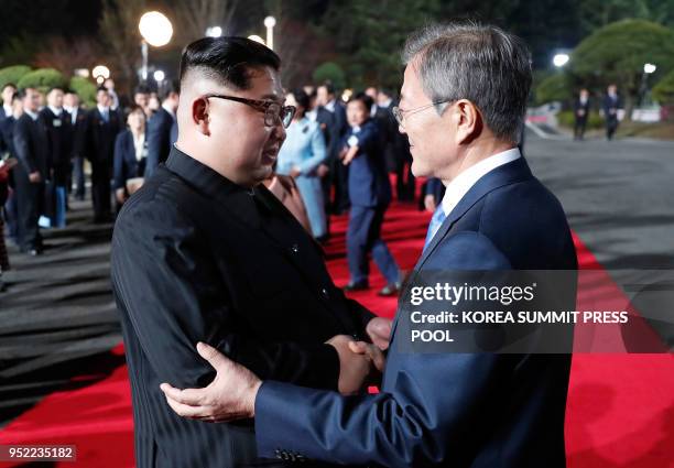 This picture taken on April 27, 2018 shows North Korea's leader Kim Jong Un and South Korea's President Moon Jae-in bidding farewell during a closing...