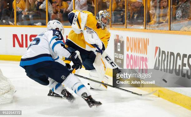 Juuse Saros of the Nashville Predators clears the puck against Mark Scheifele of the Winnipeg Jets in Game One of the Western Conference Second Round...