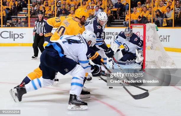 Josh Morrissey and Jacob Trouba of the Winnipeg Jets fight Colton Sissons of the Nashville Predators for a puck in front of goalie Connor Hellebuyck...