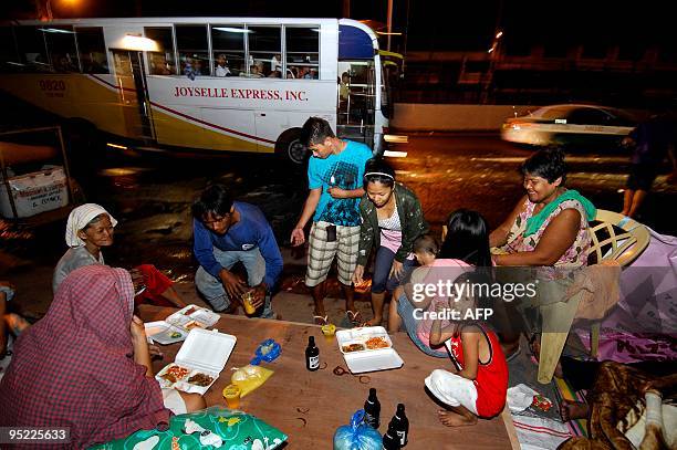 Homeless fire victims eat their christmas dinner on EDSA highway in Makati City, a suburb of Manila on December 25, 2009. They will spend Christmas...
