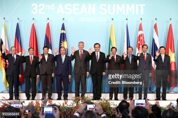 Attendees of the Association of Southeast Asian Nations Summit waves as they stand for a photograph during the summit's opening ceremony in...