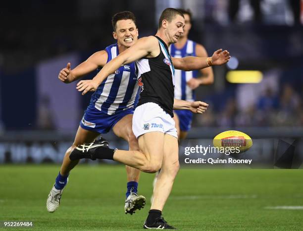 Darcy Byrne-Jones of the Power kicks whilst being tackled by Ben Jacobs of the Kangaroos during the round six AFL match between the North Melbourne...