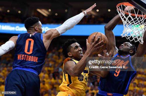 Donovan Mitchell of the Utah Jazz goes to the basket between Russell Westbrook and Jerami Grant of the Oklahoma City Thunder in the second half...