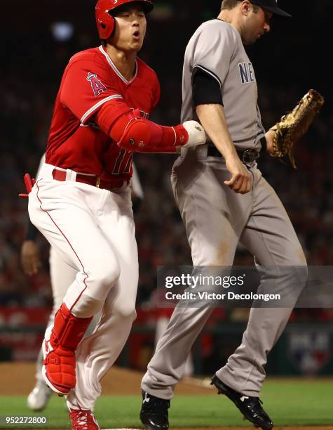 Shohei Ohtani of the Los Angeles Angels of Anaheim nearly collides with first baseman Neil Walker of the New York Yankees after Ohtani stepped on...