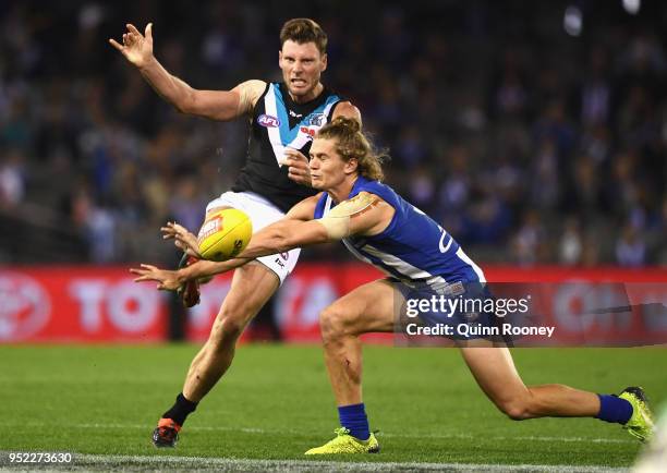 Brad Ebert of the Power kicks whilst Jed Anderson of the Kangaroos smouthers the ball during the round six AFL match between the North Melbourne...