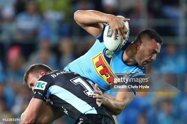 Ryan James of the Titans is tackled during the round eight NRL match between the Gold Coast Titans and Cronulla Sharks at Cbus Super Stadium on April...