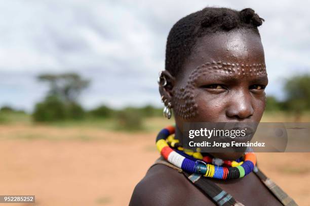 Portrait of a young Karamajong woman with traditional scars on her face.