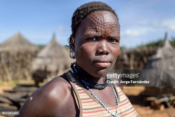 Portrait of a karamajong woman with scars on her face forming a pattern as a beauty and identity sign. I took her portrait inside one of the...