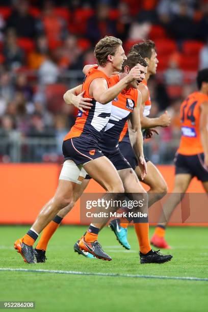 Lachie Whitfield of the Giants celebrates with his team mates after kicking a goal during the round six AFL match between the Greater Western Sydney...