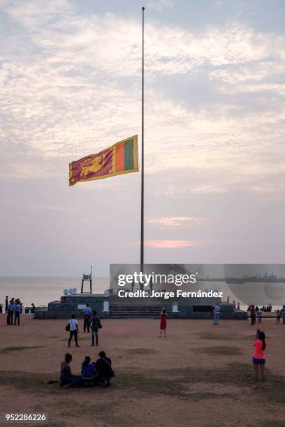 Sri Lankan honour guard lower the national flag during a ceremony at sunset.