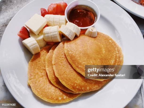 pancakes on a plate with banana, strawberry and maple syrup - strawberry syrup stock pictures, royalty-free photos & images