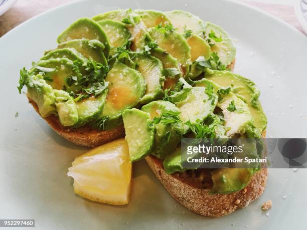 close up of sliced avocado on toasted bread served with lemon - toasted bread stock pictures, royalty-free photos & images