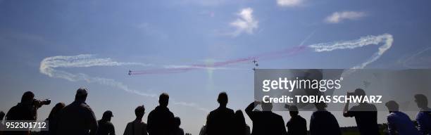 Visitors look on as the aerobatic demonstration team of the Spanish Air Force "Patrulla Aguila" performs during an airshow at the International...