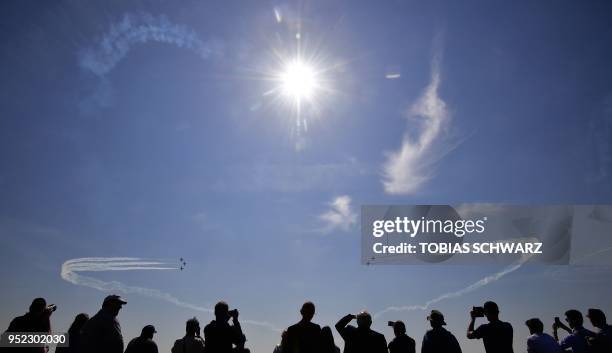 Visitors look on as the aerobatic demonstration team of the Spanish Air Force "Patrulla Aguila" performs during an airshow at the International...
