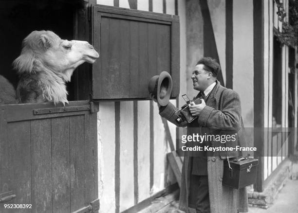 Un photographe salue un chameau dans son box avant de le photographier, à Paris, France en mai 1932.