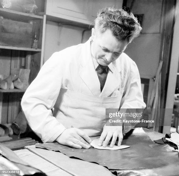 Le bottier coupe le cuir aidé par un patron, à Paris, France en 1946.