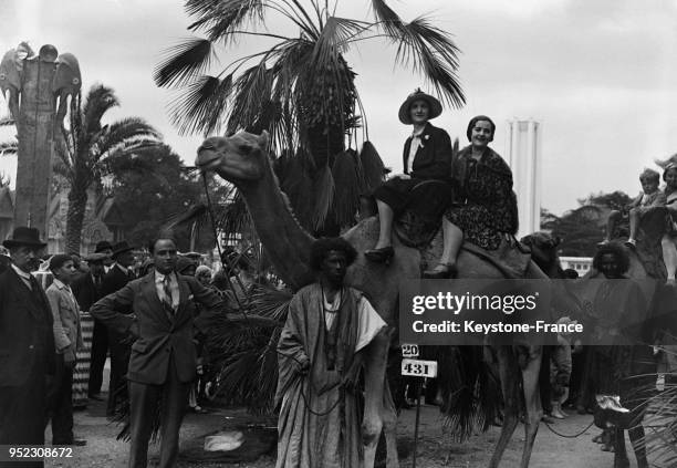 Deux femmes assises sur un chameau se promènent dans les allées de l'Exposition coloniale internationale à Paris, France en 1931.