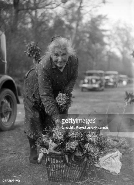 Une vieille femme vend du muguet dans les rues de Paris, France le 1 mai 1934.