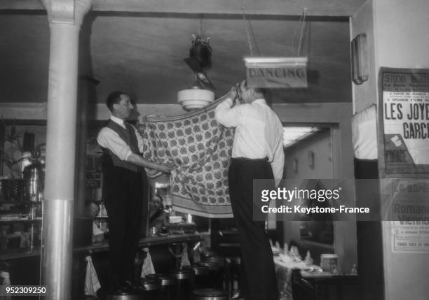 Dans une boite de nuit à Montparnasse, les garçons voilent les lumières, à Paris, France en mai 1935.