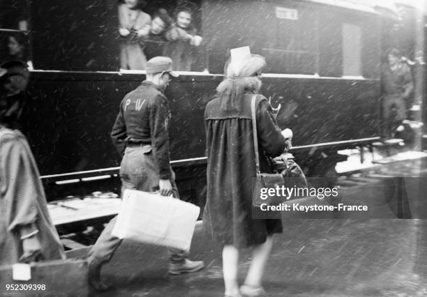 Un soldat allemand, prisonnier de guerre et réquisitionné, porte la valise d'une femme de GI en gare Saint-Lazare à Paris, France le 8 mars 1946.