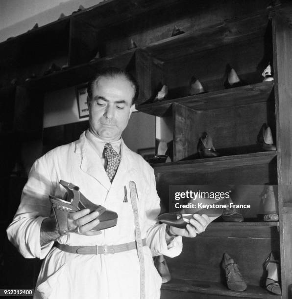 Le bottier tient dans les mains une chaussure à talon qu'il vient de finir, à Paris, France en 1946.