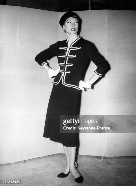 Mannequin présentant un modèle Chanel de la Collection Automne/Hiver 1956/1957: un tailleur de jersey marine avec une veste ornée de passementerie à...