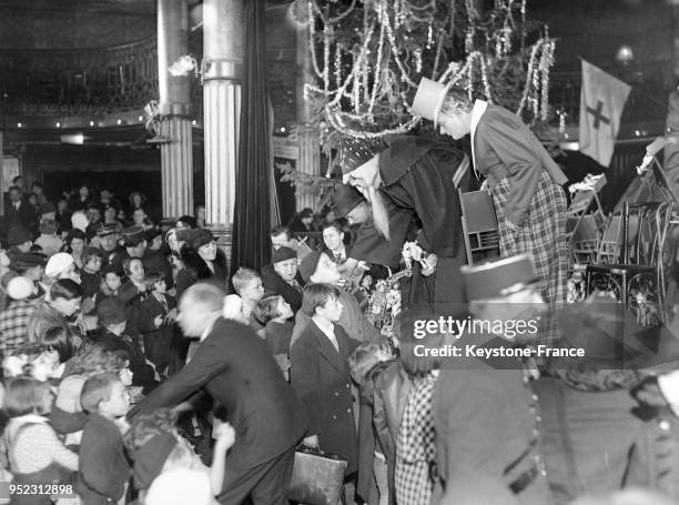 Le clown Bilboquet et le Père Noël distribuant des jouets lors de l'arbre de Noël des enfants à Paris, France, en décembre 1934.