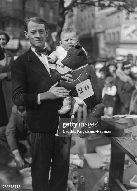 Marc Lepetit, gagnant du concours du plus bel enfant de Montparnasse, photographié avec son père et un ours en velours offert par le jury, à Paris,...