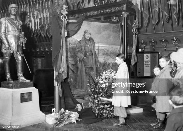 Des écoliers parisiens déposent un bouquet de fleurs au pied du portrait du roi Albert aux Invalides, à Paris, France en février 1934.