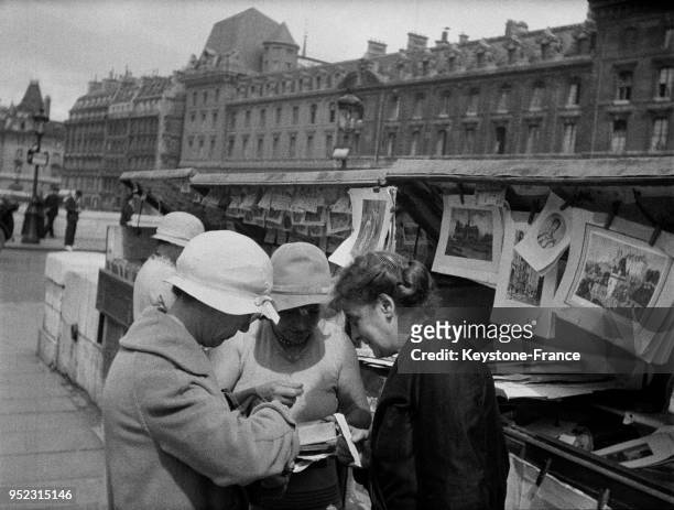 Groupe de femmes chez un bouquiniste des quais de Seine à Paris, France, en 1932.