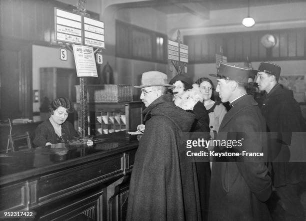 Malgré l'ordre de grève, une employée d'un bureau de poste travaille sous la protection de deux agents de police, à Paris, France en février 1934.