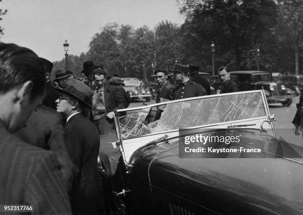 Des badauds et policiers entourent une voiture accidentée, à Paris, France en 1935.