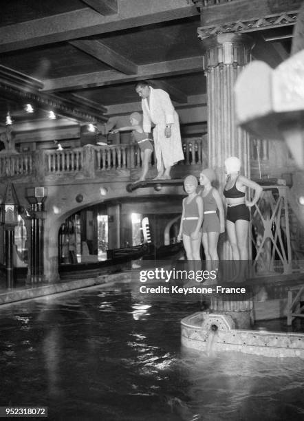 Nageuses sur le plongeon de la piscine du cabaret Lido à Paris, France en 1932.