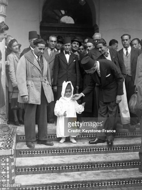 Monseur Sarouan à la sortie de la Mosquée complimente le plus jeune musulman de sa sagesse durant la cérémonie, à Paris, France en 1946.