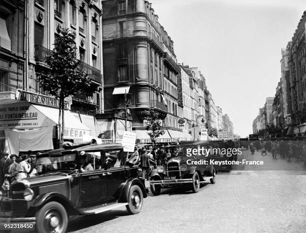 Des voitures portant des pancartes protestant contre le chômage circulant dans les rues de Paris, France en 1935.