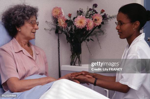 Infirmière tenant la main d'une patiente dans un hôpital à Paris, en 1995, France.