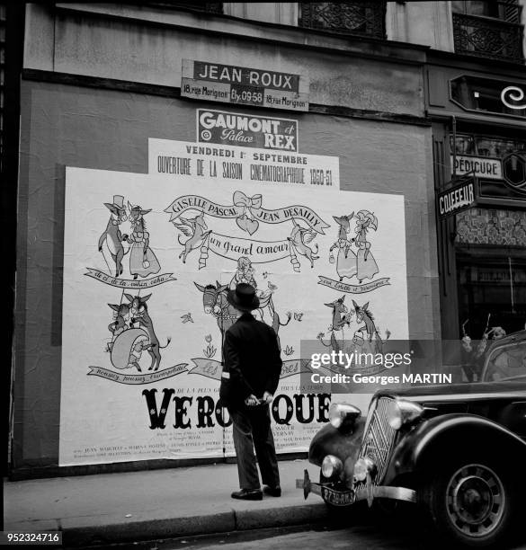 Homme dans la rue Vivienne regardant l'affiche du film 'Veronique' presente au cinema le Grand Rex et au cinema Gaumont, circa 1950 a Paris, France.